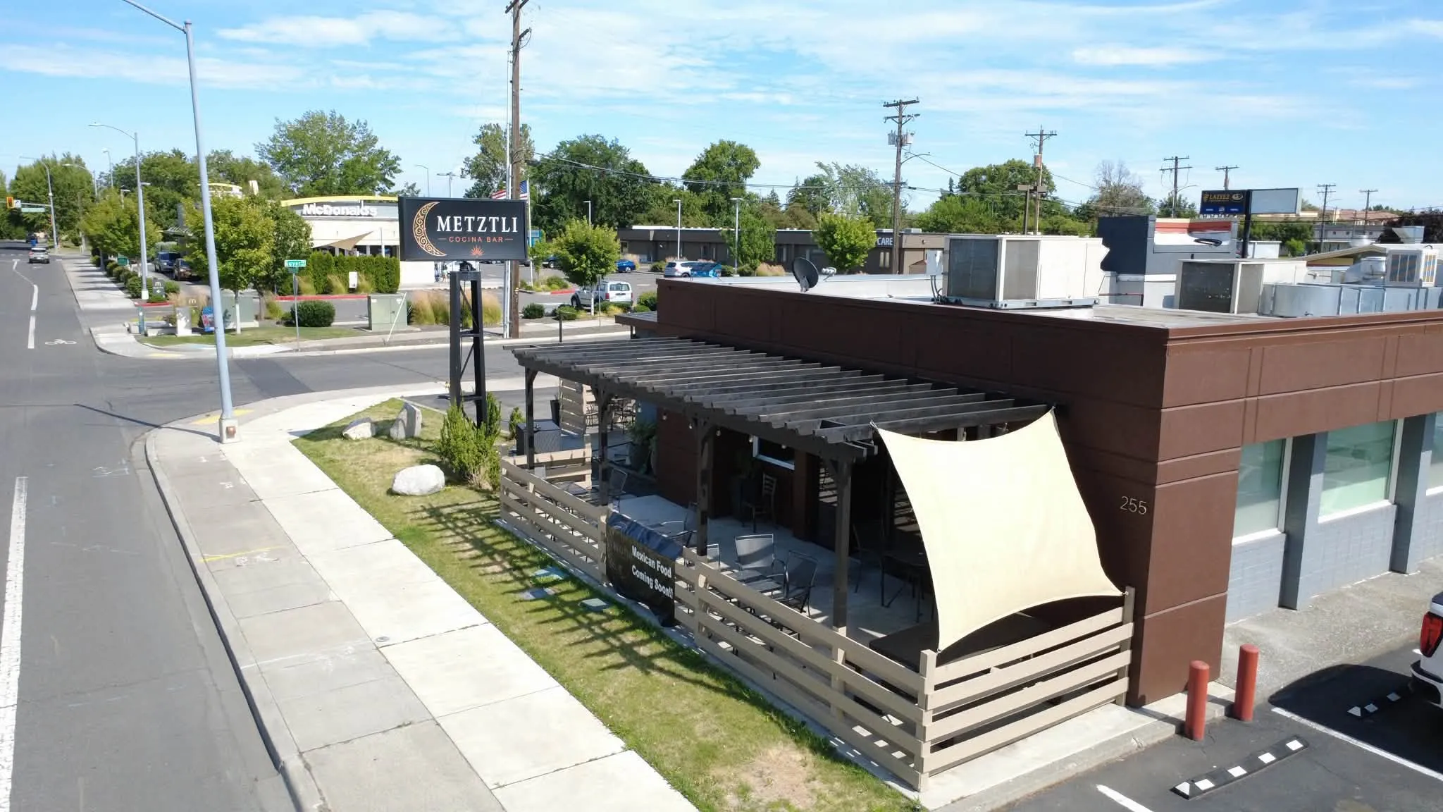Aerial view of the Metztli Cocina Bar building on Williams Boulevard in Richland with the crescent-moon sign out front and the covered patio dining area