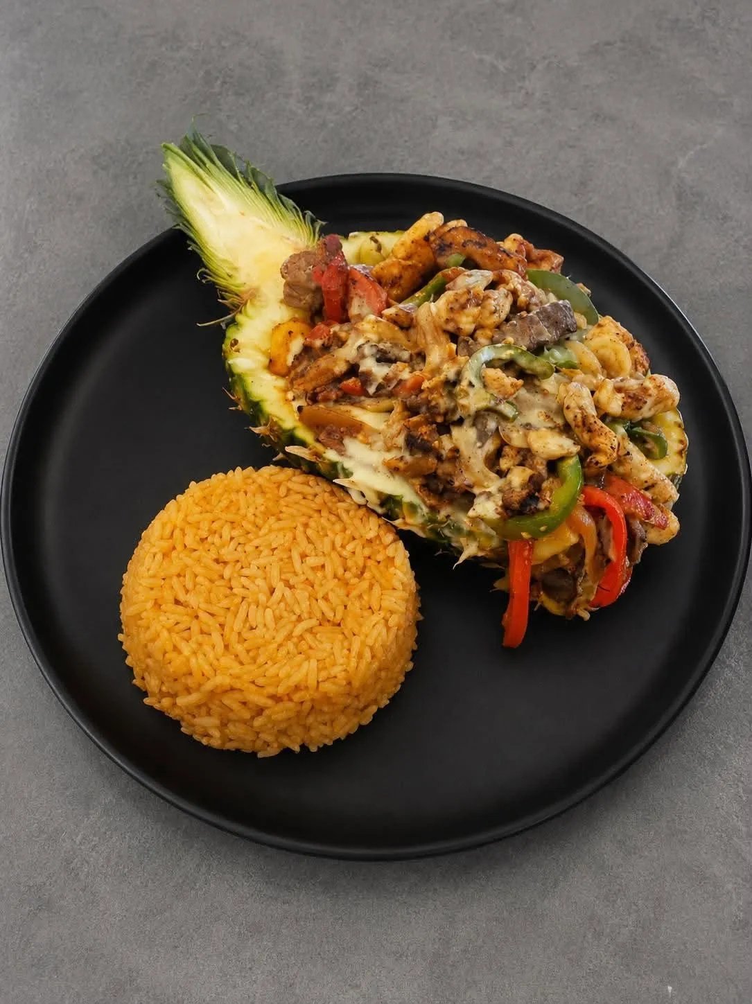 Piña rellena at Metztli — a hollowed pineapple half stuffed with grilled chicken, steak, peppers, and cheese, served alongside a scoop of Mexican rice